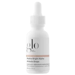 Start 87 Glo Skin Beauty Hydra-Bright Alpha Arbutin Drops - serum rozświetlające z arbutyną i kwasem mlekowym AHA, 30 ml. Biała szklana buteleczka z pipetą, minimalistyczną etykietą i logo marki Glo Skin Beauty, przedstawiona na czystym białym tle.