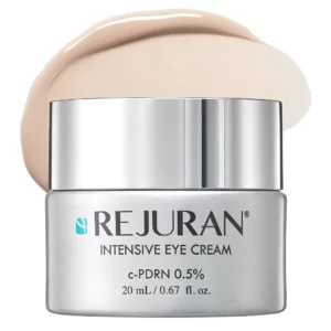 Start 45 REJURAN Intensive Eye Cream - intensywnie nawilżający i wygładzający krem pod oczy z 0,5% c-PDRN, 20 ml. Elegancki srebrny słoiczek z lustrzaną nakrętką na białym tle, otoczony smugą beżowej, kremowej konsystencji. Kosmetyk wspierający jędrność skóry i zmniejszający widoczność drobnych zmarszczek oraz kurzych łapek.