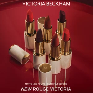 Start 47 tekst alternatywny Victoria Beckham Beauty Rouge Victoria Matte Lipstick - Aksamitny Pocałunek Luksusu - zdjęcie kolekcji sześciu pomadek w odcieniach czerwieni, burgundu i mahoniu, w eleganckich alabastrowo-złotych opakowaniach, na intensywnie czerwonym tle. Luksusowe pomadki o kremowej formule, bogatej pigmentacji i aksamitnym wykończeniu demi-matte.